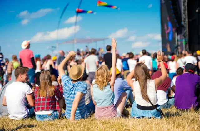 festive crowd sitting on grassy field - featured image